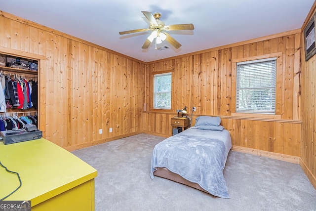 carpeted bedroom with wooden walls, a closet, multiple windows, and visible vents