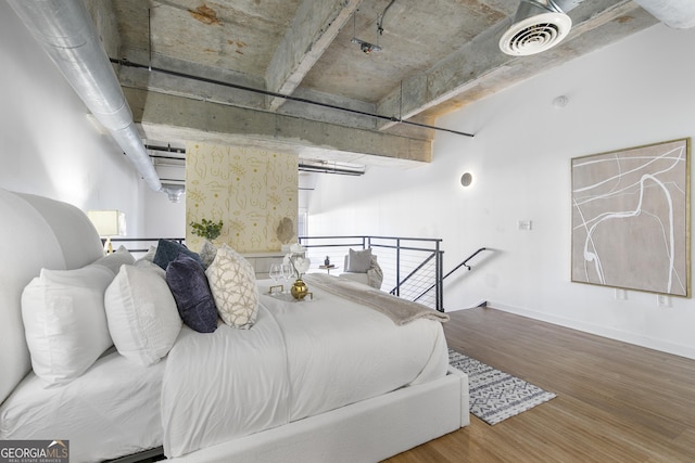 bedroom with wood finished floors, visible vents, and baseboards