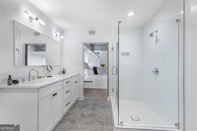 ensuite bathroom featuring a stall shower, visible vents, and a sink