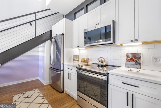 kitchen featuring light wood finished floors, appliances with stainless steel finishes, light countertops, and backsplash