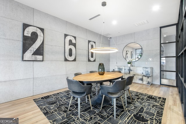 dining space featuring visible vents, tile walls, and wood finished floors