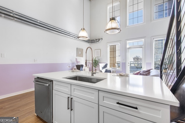 kitchen featuring wood finished floors, light countertops, stainless steel dishwasher, and a sink