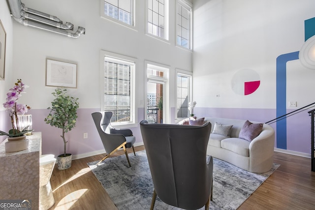 living room with a towering ceiling, baseboards, and wood finished floors