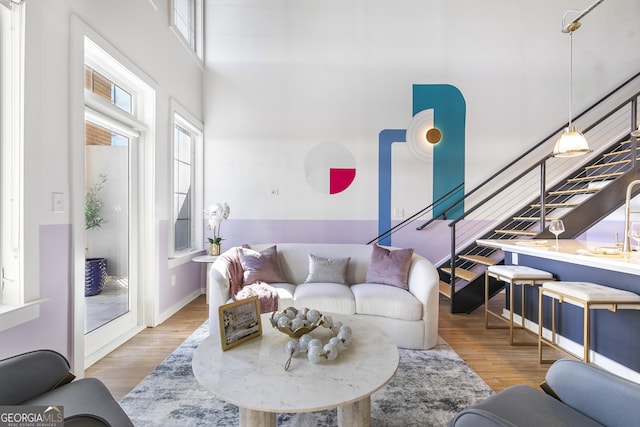 living area featuring a high ceiling, stairway, wood finished floors, and baseboards