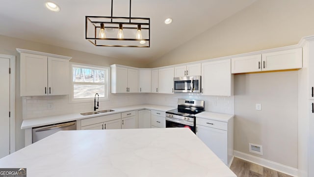 kitchen featuring lofted ceiling, a sink, white cabinets, appliances with stainless steel finishes, and decorative backsplash
