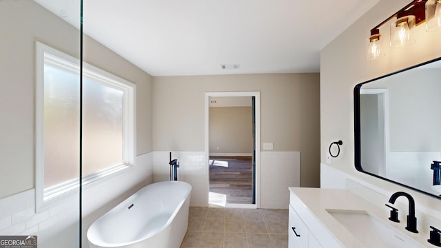 bathroom with tile walls, visible vents, vanity, a freestanding tub, and tile patterned floors