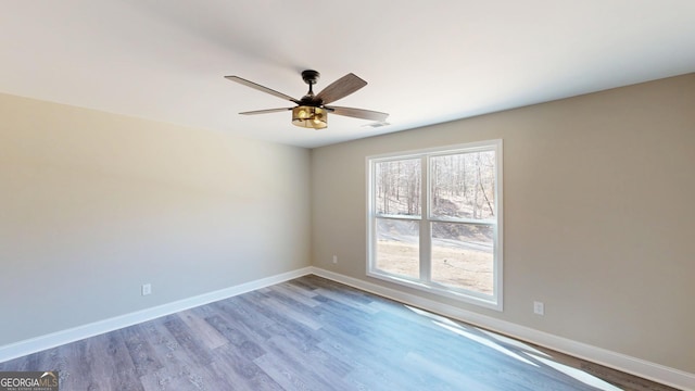 empty room with a ceiling fan, baseboards, visible vents, and wood finished floors