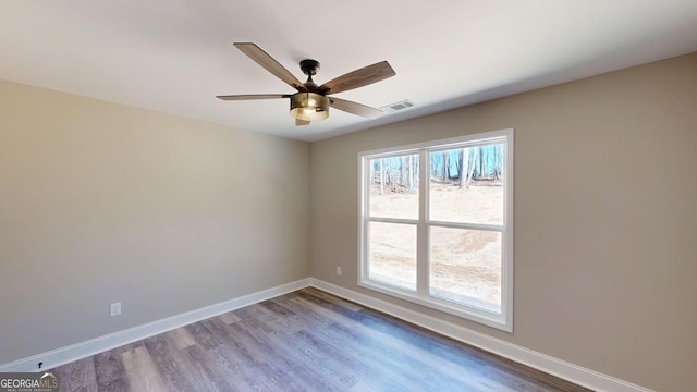empty room featuring a ceiling fan, baseboards, visible vents, and dark wood-type flooring