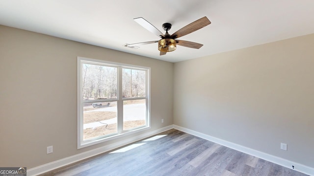 empty room featuring ceiling fan, baseboards, and wood finished floors