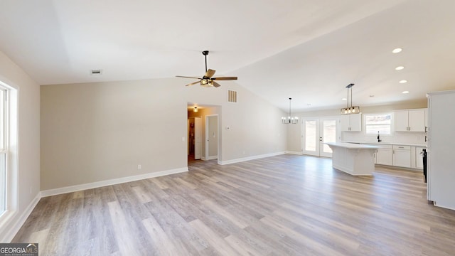 unfurnished living room with lofted ceiling, a sink, visible vents, baseboards, and light wood-type flooring