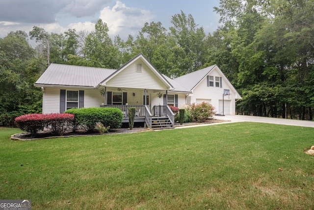 view of front of property with a garage, concrete driveway, metal roof, covered porch, and a front yard