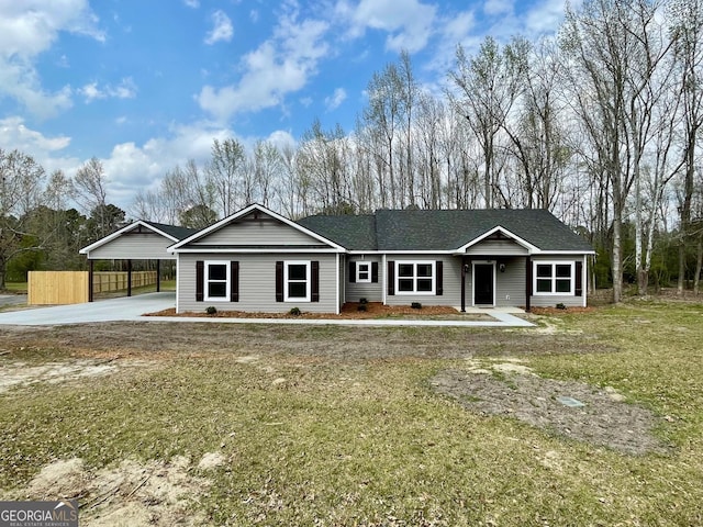 ranch-style home featuring driveway, fence, roof with shingles, a front yard, and an attached carport