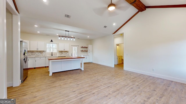 kitchen with tasteful backsplash, visible vents, lofted ceiling with beams, a sink, and butcher block countertops