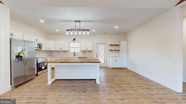 kitchen with white cabinets, light wood-type flooring, appliances with stainless steel finishes, and wooden counters