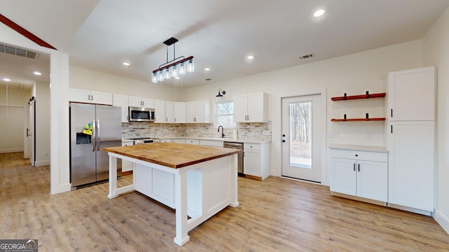 kitchen with visible vents, butcher block counters, stainless steel appliances, light wood-style floors, and a sink