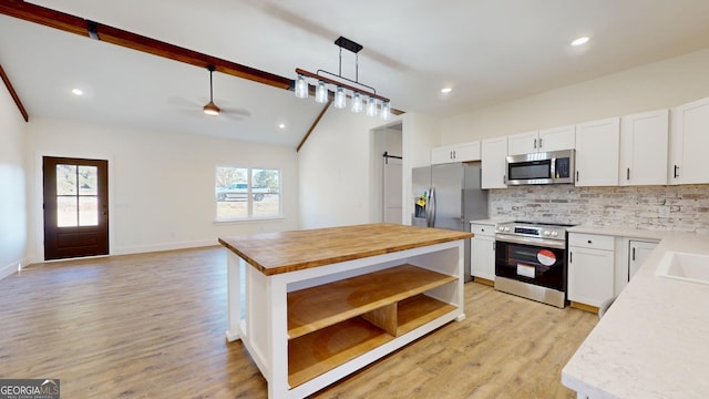 kitchen with open shelves, stainless steel appliances, tasteful backsplash, a barn door, and a kitchen island