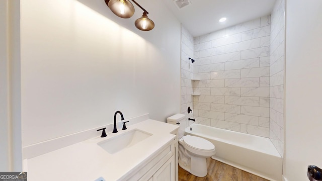 bathroom featuring toilet, wood finished floors, vanity, bathing tub / shower combination, and visible vents