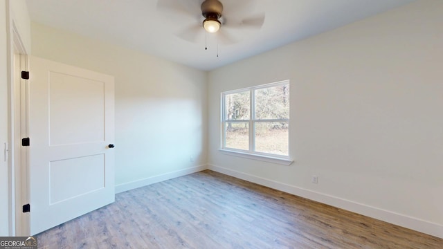 spare room featuring wood finished floors, a ceiling fan, and baseboards