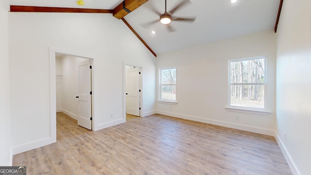 unfurnished bedroom featuring multiple windows, baseboards, beam ceiling, and wood finished floors