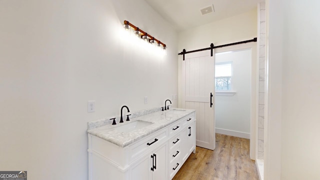 bathroom featuring double vanity, visible vents, a sink, and wood finished floors