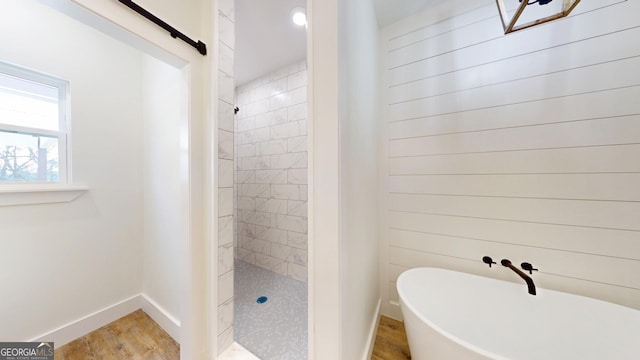 bathroom with a soaking tub, baseboards, a walk in shower, and wood finished floors