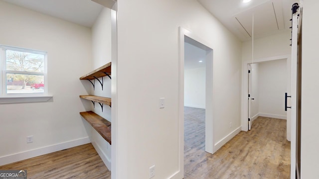 hallway with attic access, light wood-style floors, and baseboards