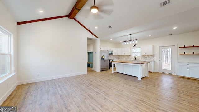 kitchen featuring vaulted ceiling with beams, stainless steel appliances, visible vents, decorative backsplash, and white cabinets