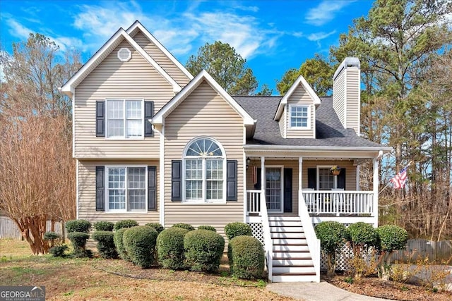 view of front facade with covered porch, roof with shingles, a chimney, and stairs