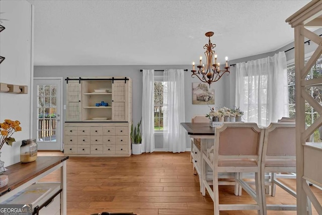 dining area featuring a textured ceiling, wood finished floors, and an inviting chandelier