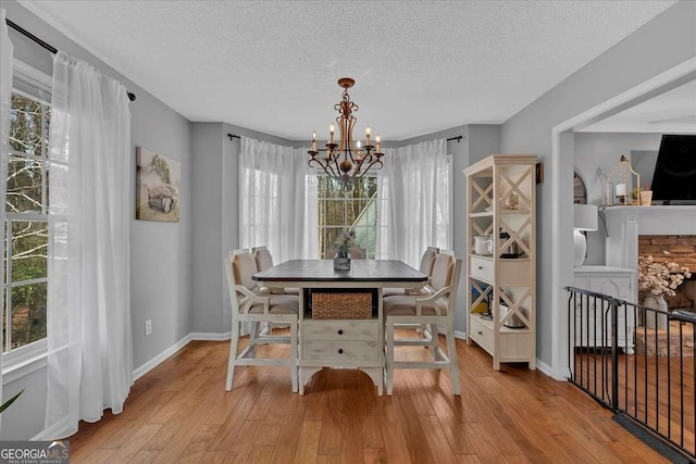 dining room featuring a chandelier, a fireplace, a textured ceiling, and hardwood / wood-style flooring