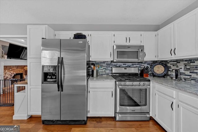 kitchen with white cabinetry, appliances with stainless steel finishes, decorative backsplash, and wood finished floors