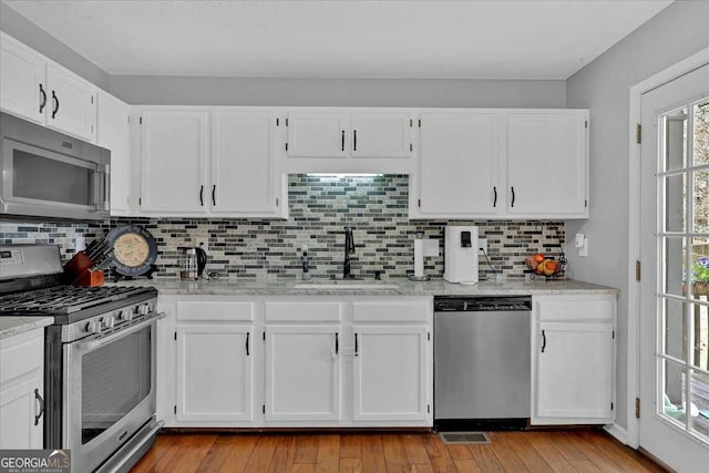 kitchen featuring appliances with stainless steel finishes, white cabinetry, and a sink