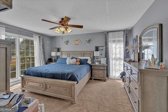 bedroom featuring a textured ceiling, ceiling fan, and light colored carpet