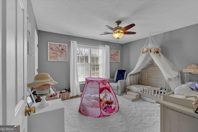 carpeted bedroom featuring a ceiling fan and a textured ceiling