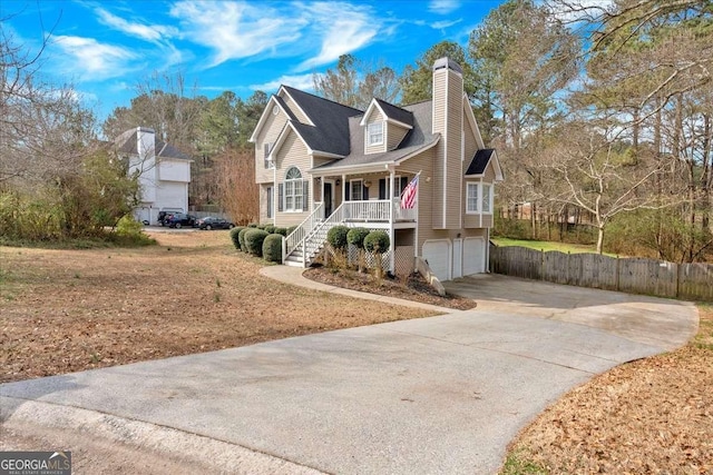 view of front of house featuring a chimney, covered porch, stairway, a garage, and driveway