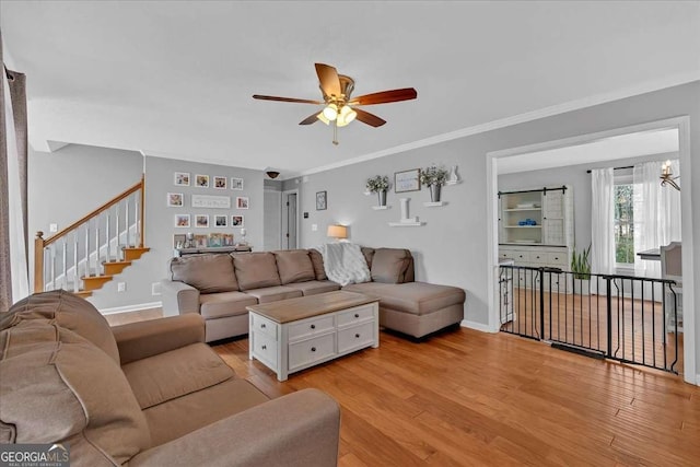 living room featuring light wood-style floors, crown molding, and baseboards