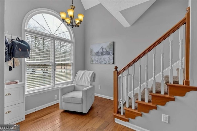 living area featuring lofted ceiling, hardwood / wood-style flooring, a notable chandelier, baseboards, and stairway