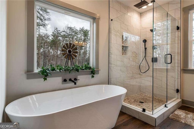 full bath with a stall shower, a freestanding bath, and wood finished floors