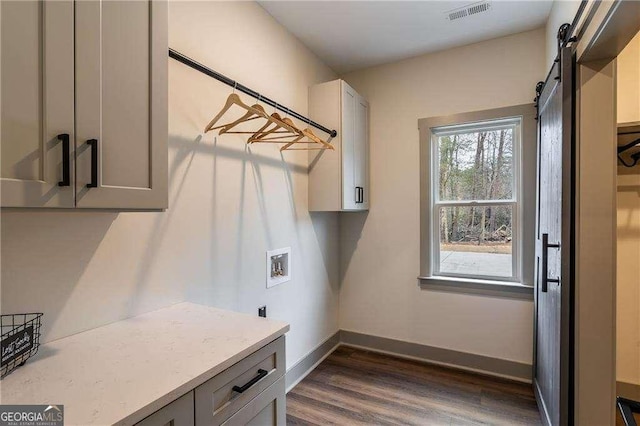 laundry room featuring cabinet space, a barn door, visible vents, baseboards, and hookup for a washing machine