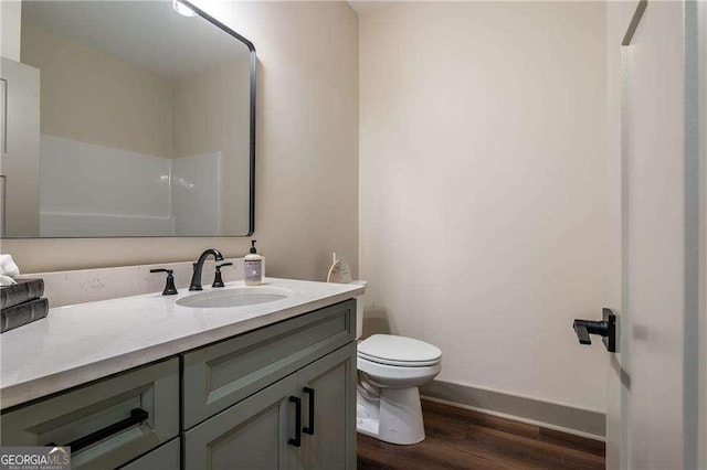 bathroom with toilet, wood finished floors, vanity, and baseboards