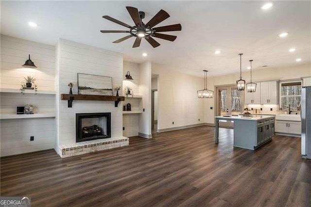 kitchen with dark wood finished floors, a kitchen island, open floor plan, freestanding refrigerator, and a kitchen bar