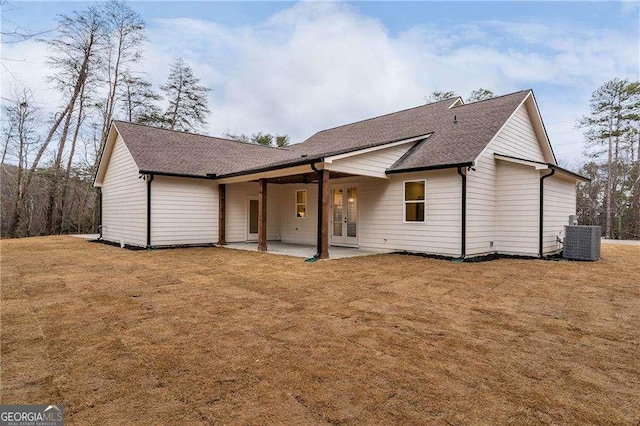 view of front of home with a patio, central AC, french doors, roof with shingles, and a front lawn