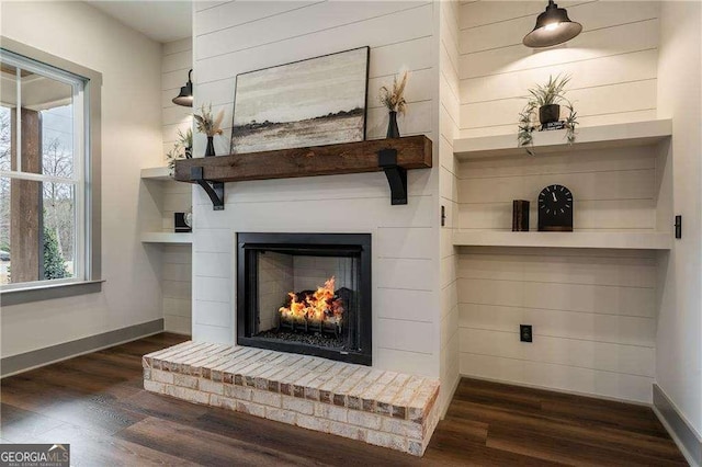 interior details featuring a lit fireplace, baseboards, and wood finished floors