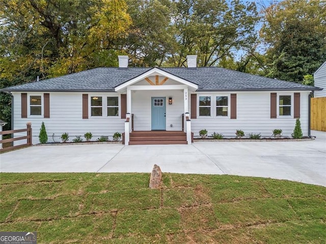 ranch-style home featuring a chimney, fence, a front lawn, and roof with shingles