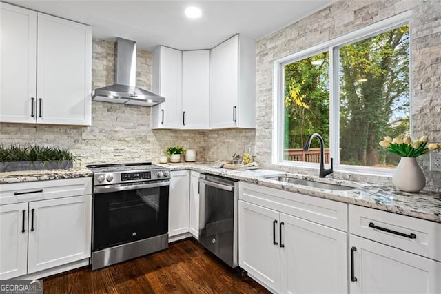 kitchen with stainless steel appliances, dark wood-type flooring, white cabinets, a sink, and wall chimney exhaust hood