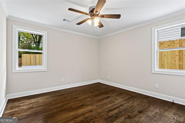 spare room with dark wood-type flooring, visible vents, ornamental molding, and baseboards