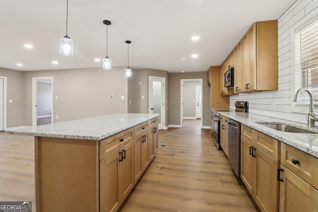 kitchen with light wood finished floors, a kitchen island, recessed lighting, a sink, and appliances with stainless steel finishes