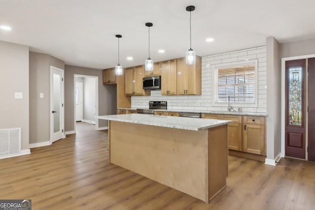 kitchen featuring wood finished floors, visible vents, a sink, appliances with stainless steel finishes, and tasteful backsplash