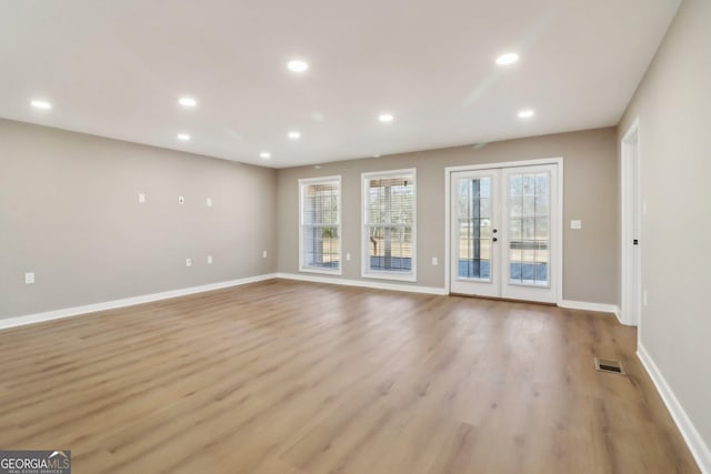 unfurnished living room featuring visible vents, light wood-style flooring, recessed lighting, french doors, and baseboards