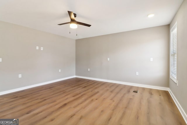 spare room featuring visible vents, baseboards, wood finished floors, and a ceiling fan